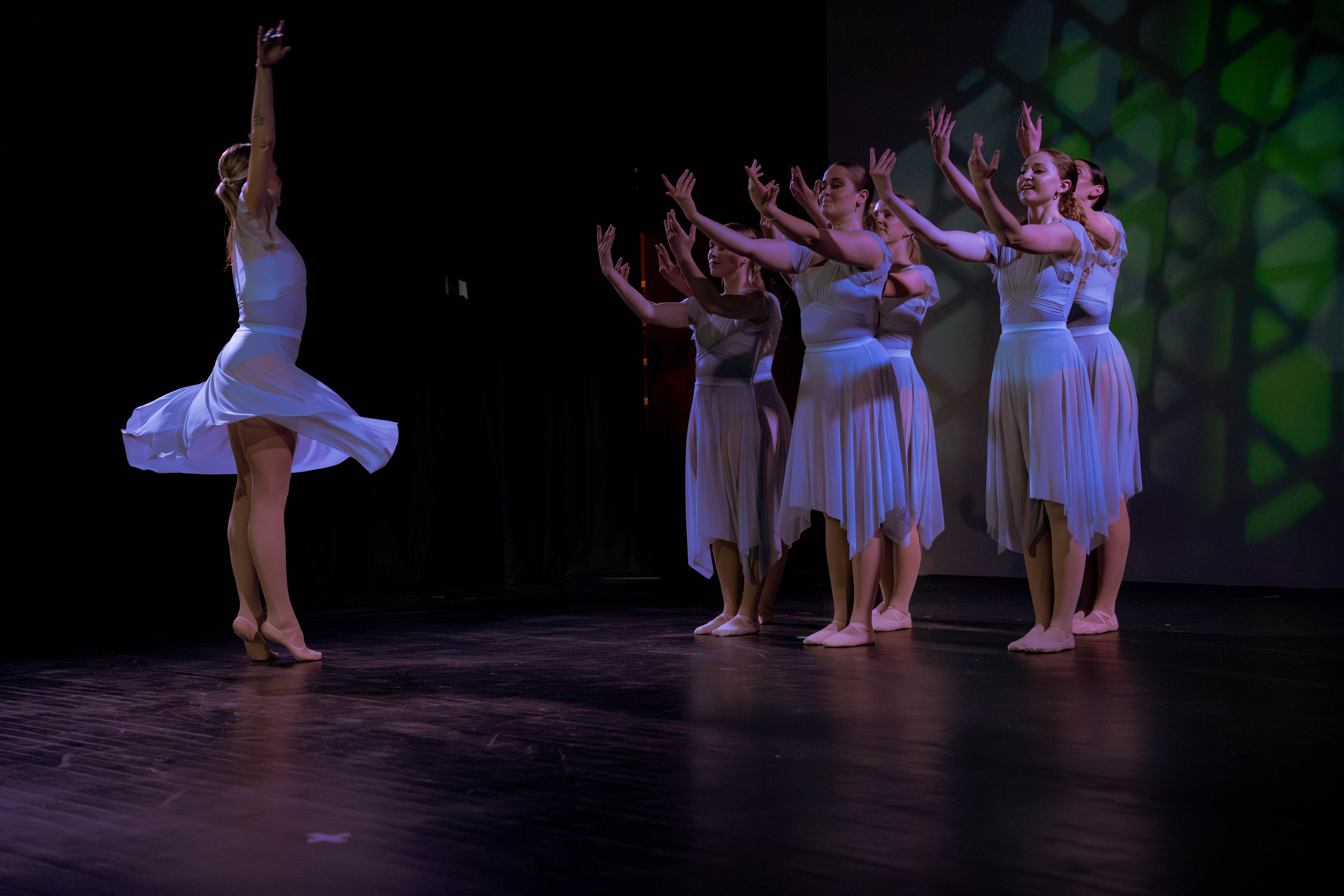 VelaDance dancer spinning in a white dress with the ensemble behind — modern dance company South Jersey